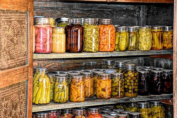 Viele mit verschiedenem Gemüse gefüllte Konservengläser stehen in einem Schrank.